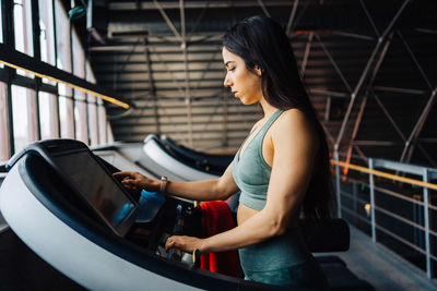 Portrait of young woman running on belt in gym