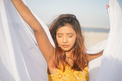 Portrait of young woman with arms raised