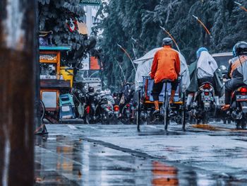 Rear view of people walking in wet city during winter
