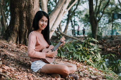 Young woman sitting on tree trunk