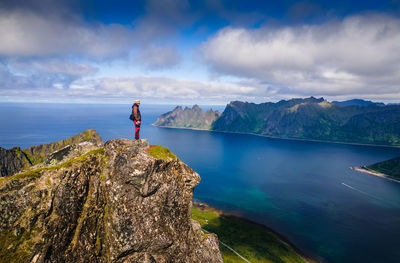 Rear view of man standing on cliff against sky