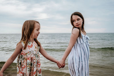 Portrait of sisters holding hands and walking near a lake