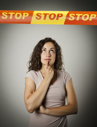 Portrait of beautiful young woman standing against wall