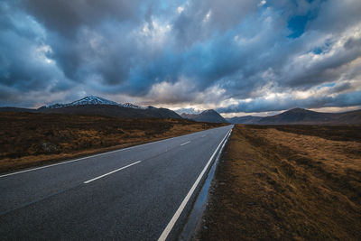 Road leading towards mountain range against sky