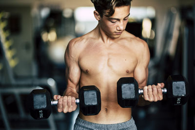 Male teenager exercising with dumbbells