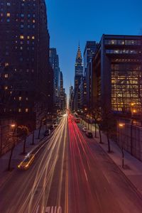 Light trails on city street amidst buildings at night