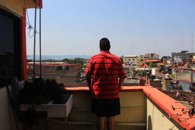 Rear view of man standing by buildings against sky