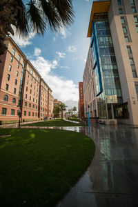 Buildings by footpath against sky in city