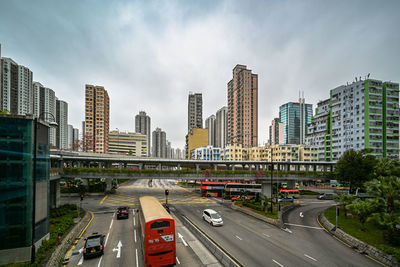 Traffic on road by buildings against sky in city