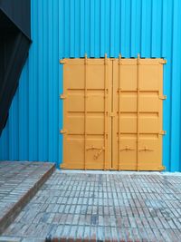 Closed yellow metal grate against blue wall