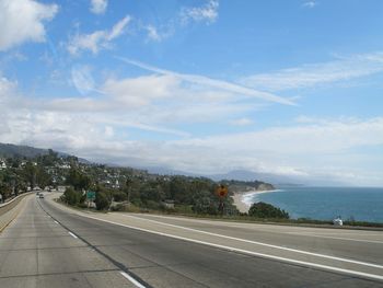 Road passing through city against sky