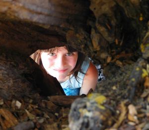 High angle portrait of girl seen through tree hole