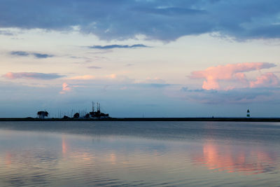 Pink colored clouds reflected in the sea and coast with lighthouse of schleimünde - dusk