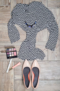 Flat lay of womenswear and make-up on wooden floor