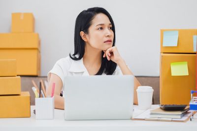 Young woman using mobile phone while sitting on table