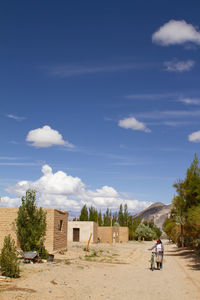 Woman with bicycle against houses and sky