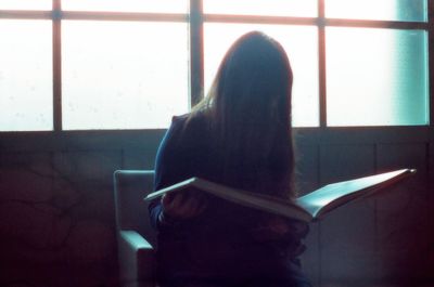 Rear view of woman sitting on floor