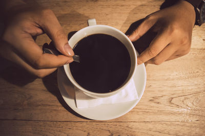 Cropped hands of person holding coffee cup on table