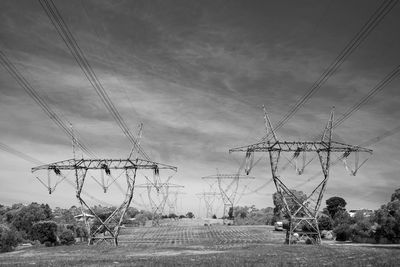 Low angle view of electricity pylon on field against sky