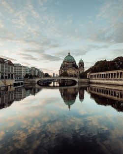 Reflection of berlin cathedral and bridge on canal during sunset