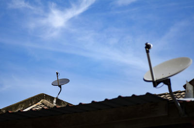 Low angle view of telephone pole on roof of building against sky