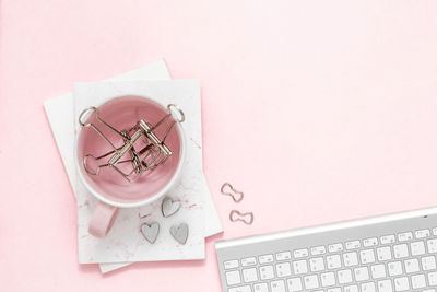 A feminine workspace, keyboard of a computer on pink background with copy space