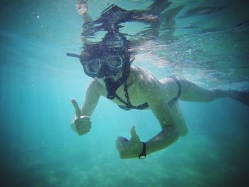 Portrait of woman showing thumbs up while snorkeling undersea