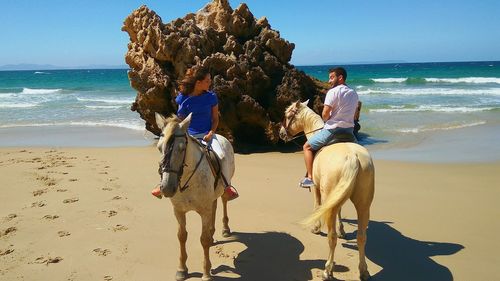 Man and woman riding horses at beach