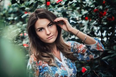 Portrait of beautiful young woman posing against trees