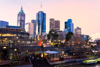 Illuminated buildings in city against sky at dusk