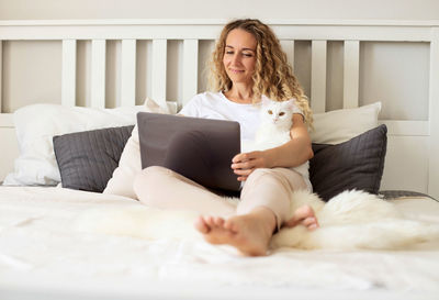 Smiling woman with cat using laptop at home