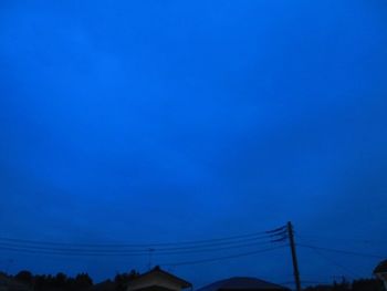 Low angle view of electricity pylon against blue sky