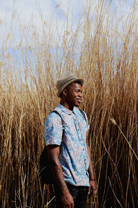 Young man standing amidst grass on field