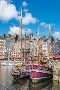 Fishing boats moored in city against sky