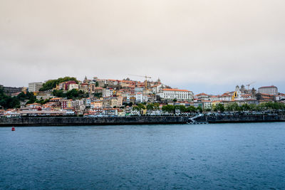 Buildings by sea against sky