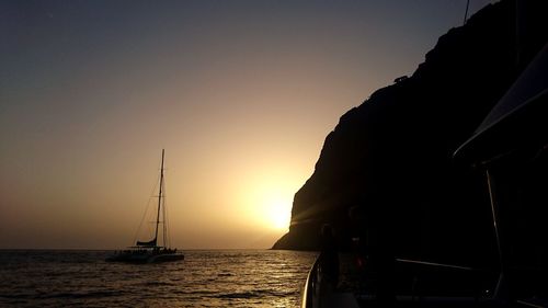 Silhouette of sailboat on sea during sunset