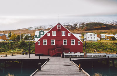 Pier amidst lake and buildings against sky