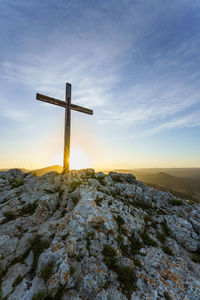 Christian symbol, wooden catholic cross on the top of a mountain at sunrise.