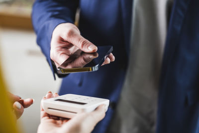 Hand of young businessman paying through smart phone