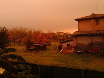 Houses and trees on field against sky