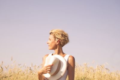 Woman holding hand while standing against clear sky