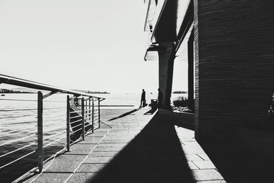 Man on bridge over sea against clear sky