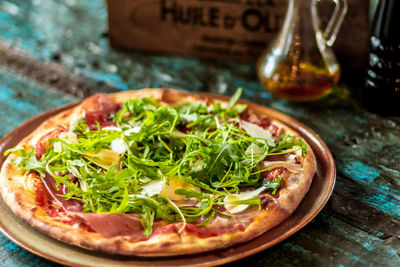 Close-up of pizza with arugula leaves in plate on table