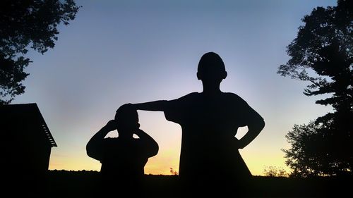 Silhouette boy photographing against sky