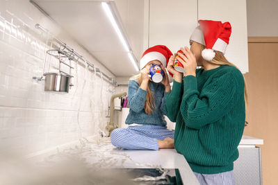 Mother and daughter drinking hot chocolate in kitchen
