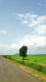 Road amidst field against sky