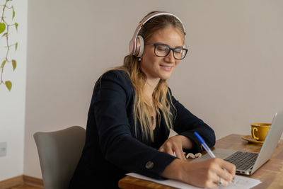 Woman working at home with laptop and papers on desk and headphones. home office . gray notebook 