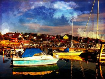 Boats in harbor against cloudy sky