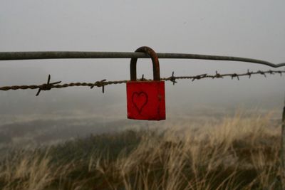 Close-up of padlocks hanging on metal structure against sky
