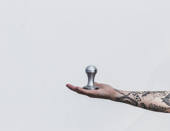 Close-up of hand holding lamp against white background
